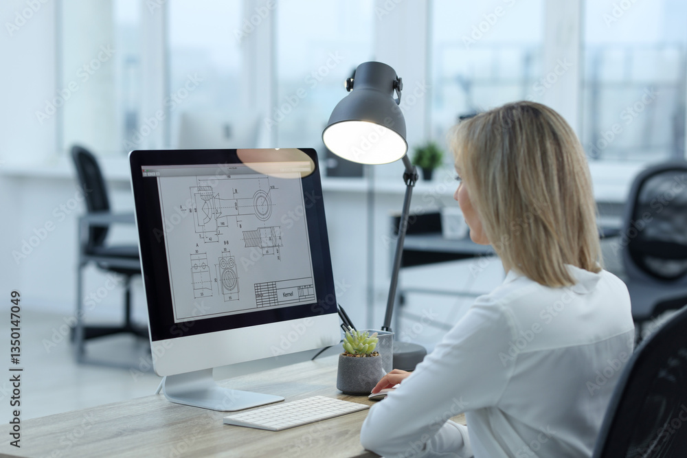 Poster technician making digital engineering drawing on computer at desk in office, back view