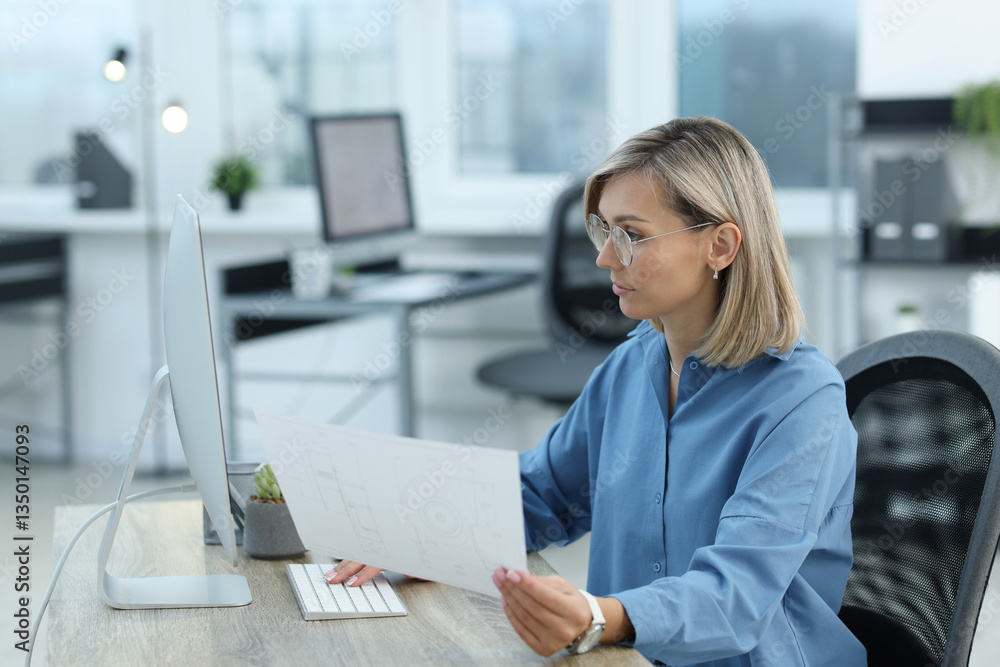 Poster technician making digital engineering drawing on computer at desk in office