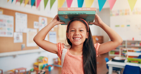 Girl, smile and books on head at school, portrait and excited for education, story or development. Child, happy and learning in classroom, study and scholarship with reading at academy in Colombia