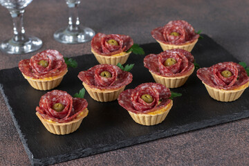 Tartlets in shape of roses with sausage salami and olives, festive snack