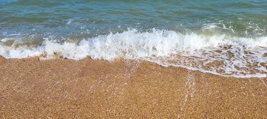 Beautiful azure sea with white foam and a beach on a clear sunny day