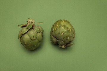 Fototapeta premium Fresh artichoke on green background. Two whole green artichokes mockup.