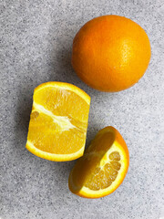 One whole and one cut in half oranges lie on a white surface with dark spots, close-up, top view. Ripe, juicy, oranges. Vitamin charge. Proper nutrition.