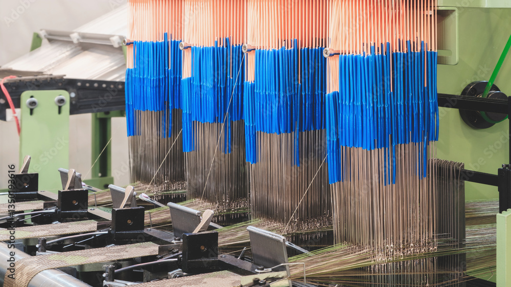 Poster A machine is weaving a piece of fabric. The machine is made up of many parts, including a large metal piece that is connected to a hose