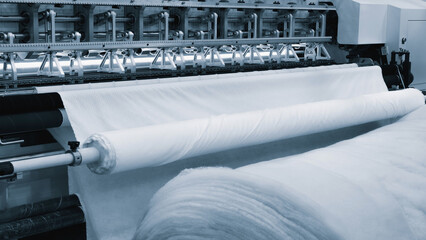A machine is weaving a piece of fabric. The machine is made up of many parts, including a large...