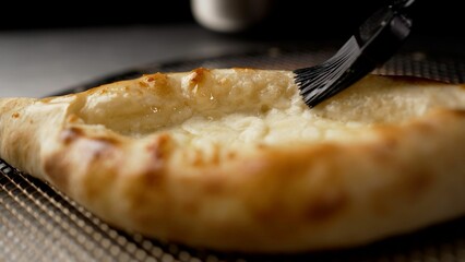 Professional chef brushing melted butter on adjarian khachapuri, a traditional georgian cheese-filled bread
