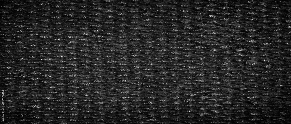 Poster Close up of black surface of processed stone with lots of texture. The textured background has a rough textured surface with a geometric repeating pattern