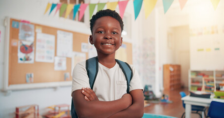 Arms crossed, happy and education with black boy in classroom for learning, future and youth. Scholarship, academy and growth with portrait of kid in school for child development, knowledge or lesson © peopleimages.com