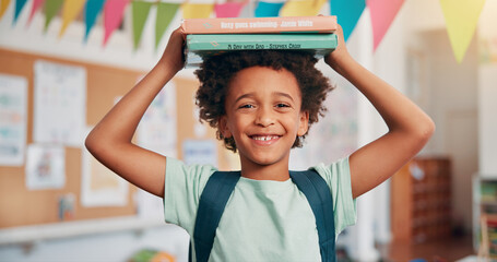 Boy, smile and books on head in classroom, portrait and excited for education, story or...