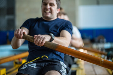 Breathless athlete struggle with exertion while handling oars on rowing simulator. Intense crew...