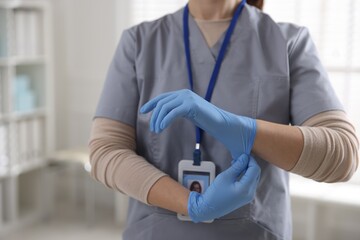 Medical worker putting on gloves in hospital, closeup