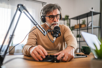 senior man host with headphones set up equipment prepare for podcast