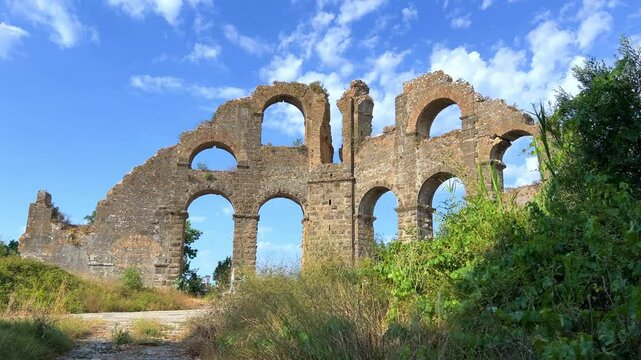 The ancient city of Aspendos. Ruins of aqueducts of Aspendos Acropolis. T&uuml;rkiye. Historical siphon of Aspendos Aqueduct with olive trees, Antalya. 4K