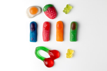 Colorful gummy candy assortment including gummy fingers, bears, cherries and fried egg on white background