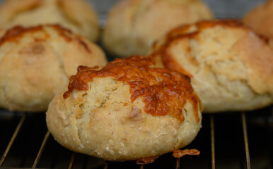 Freshly baked cheese rolls cooling on a wire rack in a cozy kitchen atmosphere during late afternoon sunlight