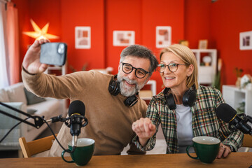 man and woman record podcast and take a self portrait on mobile phone