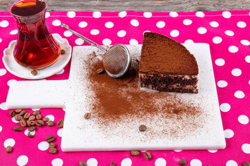 Side View of a Tiramisu Slice. Tiramisu cake decorated with coffee powder on a marble plate....