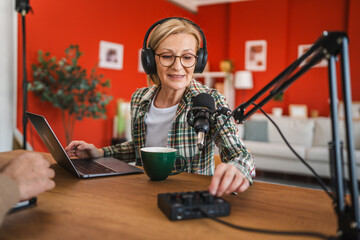 mature woman host with headphones set up equipment prepare for podcast