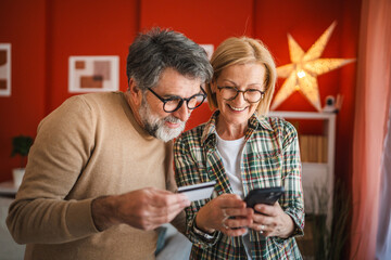 mature couple use mobile phone and credit card for online shopping