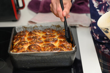Freshly baked sweet rolls being glazed in a cozy kitchen filled with warmth and delightful aromas