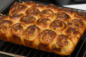 Deliciously baked bread rolls topped with spices fresh out of the oven, tempting aroma fills the air in a cozy kitchen