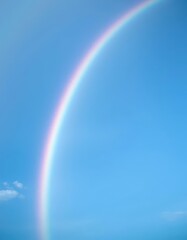 Vibrant rainbow arc spanning a vast, clear blue sky, beautiful, sunshine