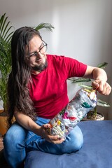 Man recycling plastic at home. Plastic bottles filled with packaging. Making 'Bottles of love'....
