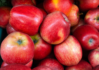 Fresh red apples from a farm orchard are neatly arranged in a crate on a supermarket shelf. The fruits look ripe and delicious, ready for sale. A natural product, ideal for healthy eating and cooking