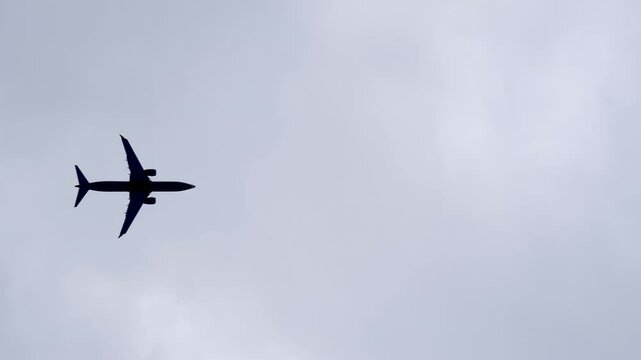 Lower view of an airplane flying above the camera in cloudy sky. Aircraft overhead bottom view.