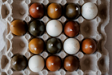 Stylish candles in the shape of painted chicken eggs. Easter theme, Easter egg candles in paper egg trays on a minimalist background, Easter aesthetics