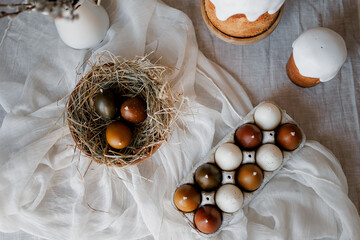 Easter table decorated with a homemade Easter cake on a stand, painted eggs and candles, morning...