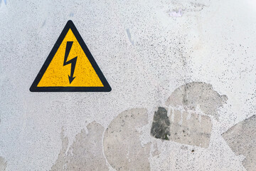 Warning sign indicating high voltage on a weathered concrete surface near an electrical installation