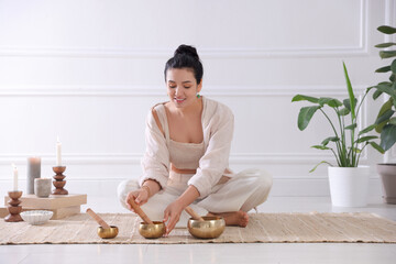 Woman with singing bowls on floor indoors