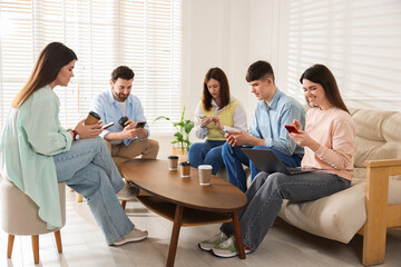 Fototapeta premium Internet addiction. Group of friends with gadgets and coffee at table indoors