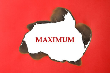Word Maximum on white background, view through burnt hole in red paper