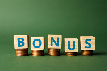 Word Bonus made of cubes with letters on stacked coins against green background