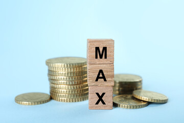 Wooden cubes with word Max and coins on light blue background