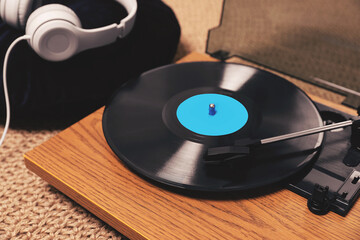 Turntable with vinyl record and headphones on floor, closeup