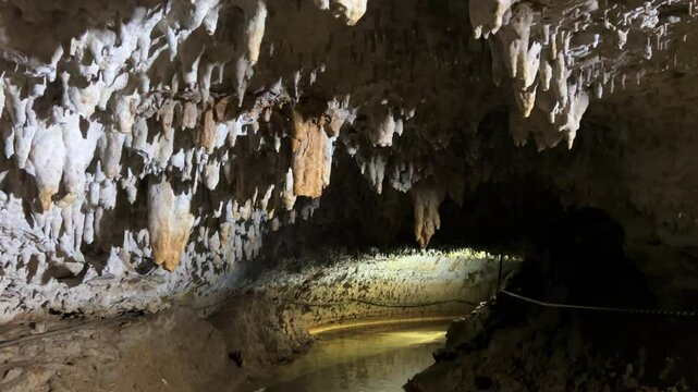 The bright and colorful Abrskil cave. A gallery-type cave in the mountains of Abkhazia with many stalactites and stalagmites, colorful lighting. Otapskaya (Otap cave). 4K