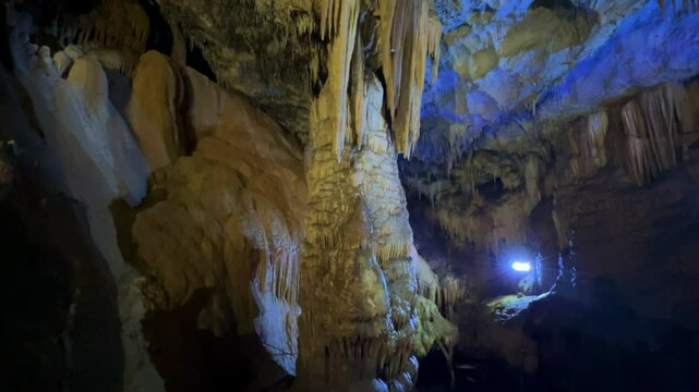 The bright and colorful Abrskil cave. A gallery-type cave in the mountains of Abkhazia with many stalactites and stalagmites, colorful lighting. Otapskaya (Otap cave). 4K