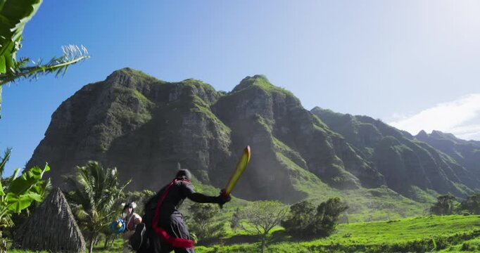 Ninja leaping over flying panda on wires and running to fight female warrior with view of beautiful Hawaiian mountains - low shot