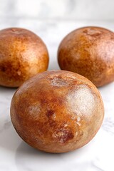 Three deliciously golden baked buns on a pristine marble surface