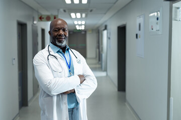 Confident doctor standing in hospital corridor with stethoscope, ready for duty, copy space