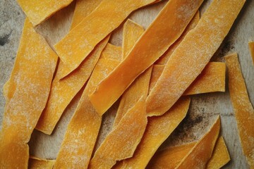 Dried Mango Slices on Textured Surface, Close-up View of Fruit Pieces, Candied Snack, Sweet Treat, Orange and Yellow Food