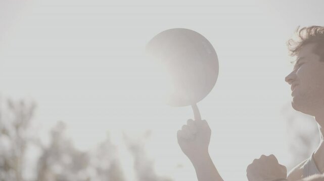Atmospheric backlit light sillhouette Brunette sport caucasian guy spinning basketball on one finger outdoor. Skilled sportsman playing game. Active sport healthy lifestyle. Concept outside activity. - Powered by Adobe