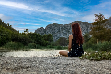Woman enjoys, a peaceful moment by the river, surrounded by mountains, embracing yoga, mindfulness, travel  and healthy living in nature. Escape for relaxation, wellness, and outdoor adventure.