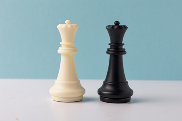 White and black queen chess pieces standing on white surface