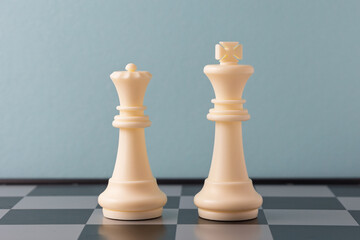 White king and queen chess pieces standing on a chessboard