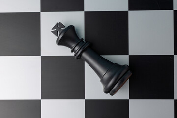 Fallen black king chess piece lying on chessboard
