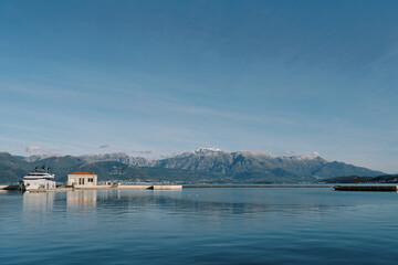 Naklejka premium Motor yacht moored to a pier with a small building in the background of a mountain range
